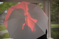 silhouette of a a couple about to kiss behind a red umbrella