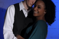 Mixed couple in front of a blue gelled background.
