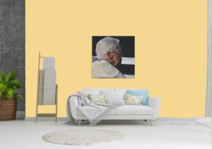 picture of a room with 1 sofa and a large portrait above it of an older woman in profile. 