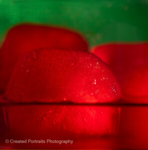 red colored ice cubes melting in front of a green background